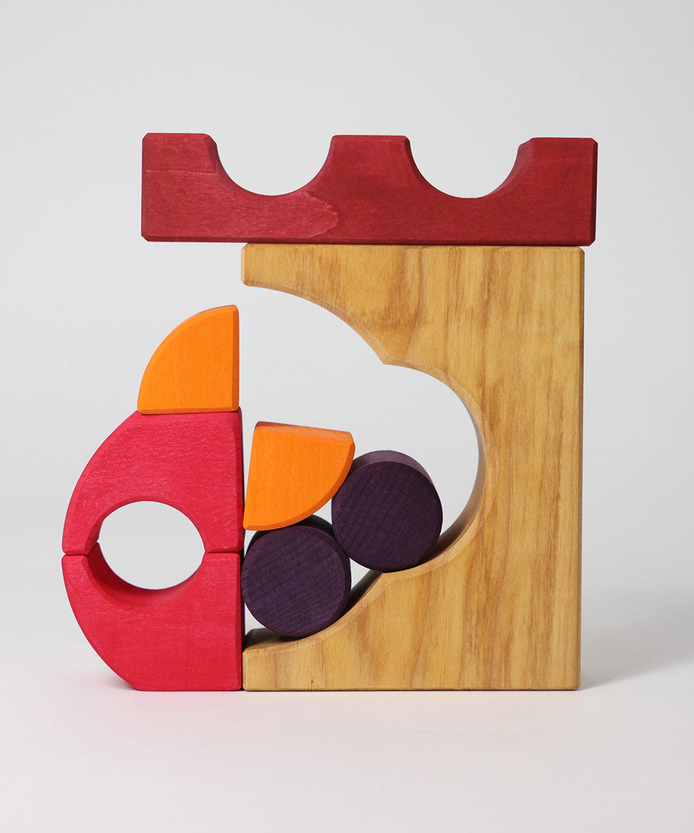 A stack created using pieces from the Grimm's red building set. The stack  resembles the shape of a castle. These Grimm's toys are part of a wide range of wooden toys available here at Babipur. 