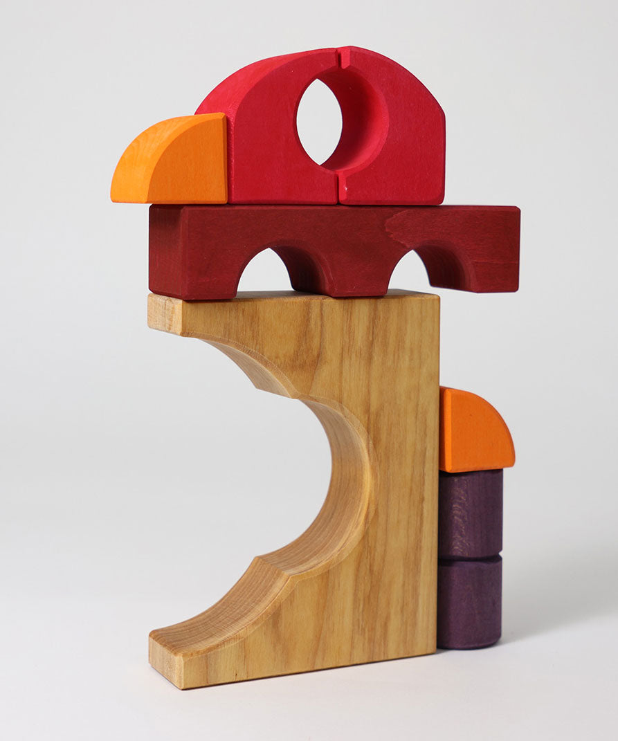 A stack created using pieces from the Grimm's red building set. The stack loosely resembles the shape of a bird. These Grimm's toys are part of a wide range of wooden toys available here at Babipur. 