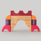 A stack created using pieces from the Grimm's red building set. The stack  resembles the shape of a castle. These Grimm's toys are part of a wide range of wooden toys available here at Babipur. 