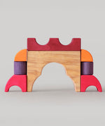A stack created using pieces from the Grimm's red building set. The stack  resembles the shape of a castle. These Grimm's toys are part of a wide range of wooden toys available here at Babipur. 