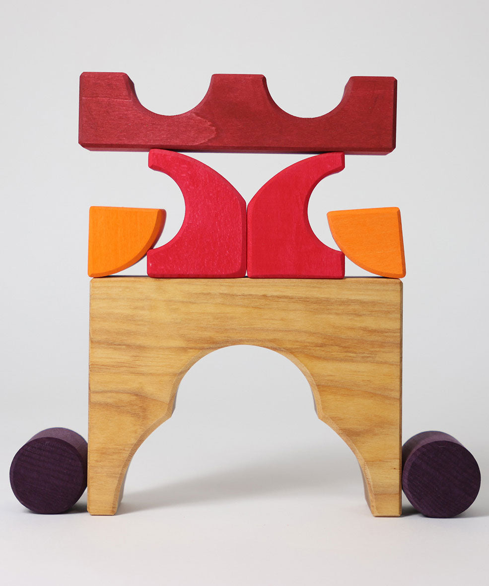 A stack created using pieces from the Grimm's red building set. The stack  resembles the shape of a castle. These Grimm's toys are part of a wide range of wooden toys available here at Babipur. 