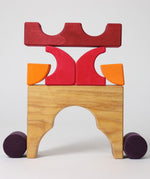 A stack created using pieces from the Grimm's red building set. The stack  resembles the shape of a castle. These Grimm's toys are part of a wide range of wooden toys available here at Babipur. 