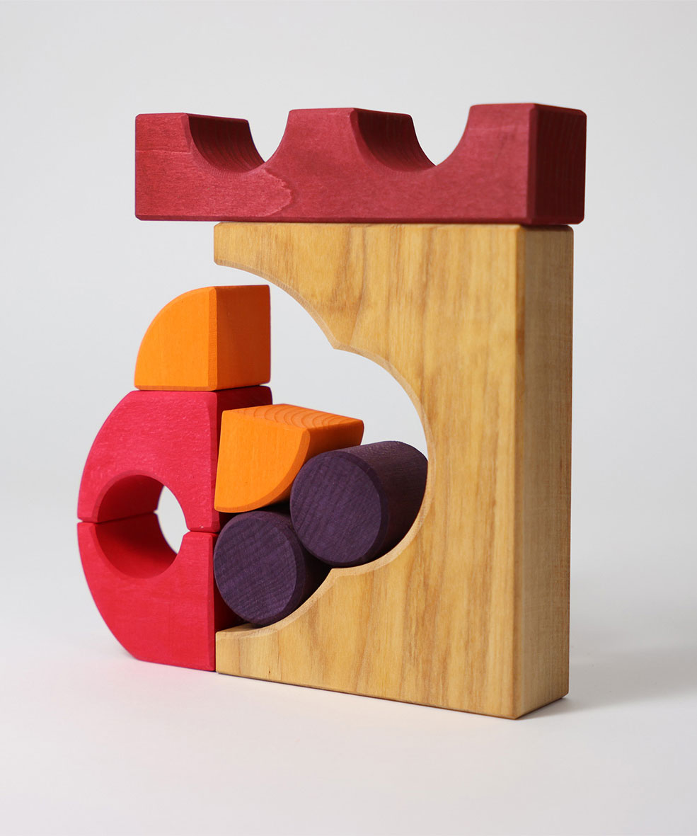 A stack created using pieces from the Grimm's red building set. The stack  resembles the shape of a castle. These Grimm's toys are part of a wide range of wooden toys available here at Babipur. 