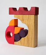 A stack created using pieces from the Grimm's red building set. The stack  resembles the shape of a castle. These Grimm's toys are part of a wide range of wooden toys available here at Babipur. 