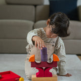 A child playing with the Grimm's red car stacking puzzle building block set stacking the pieces on top of each other. These Grimm's toys are part of a wide range of wooden toys available here at Babipur. 