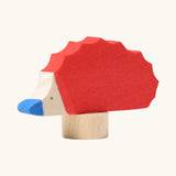 Front of Grimm's handcrafted wooden red hedgehog decorative figure showing hand painted blue nose and eyes