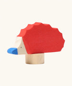 Front of Grimm's handcrafted wooden red hedgehog decorative figure showing hand painted blue nose and eyes