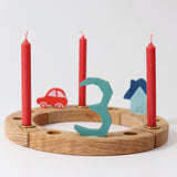 Grimm's Red 10% beeswax candles placed on a natural celebration ring. 