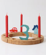 Grimm's Red 10% beeswax candles placed on a natural celebration ring. 