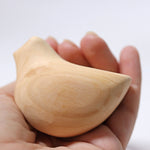 A close up of the Grimm's wooden relaxing bird toy in the placed in the palm of an adult's hand.