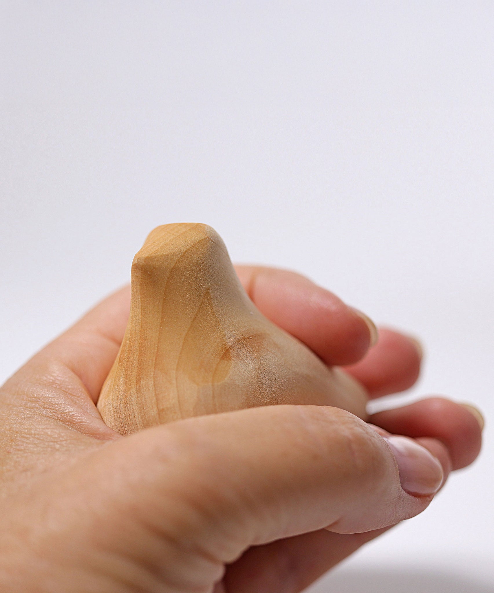 A close up of the Grimm's wooden relaxing bird toy being held in an adult's hand.