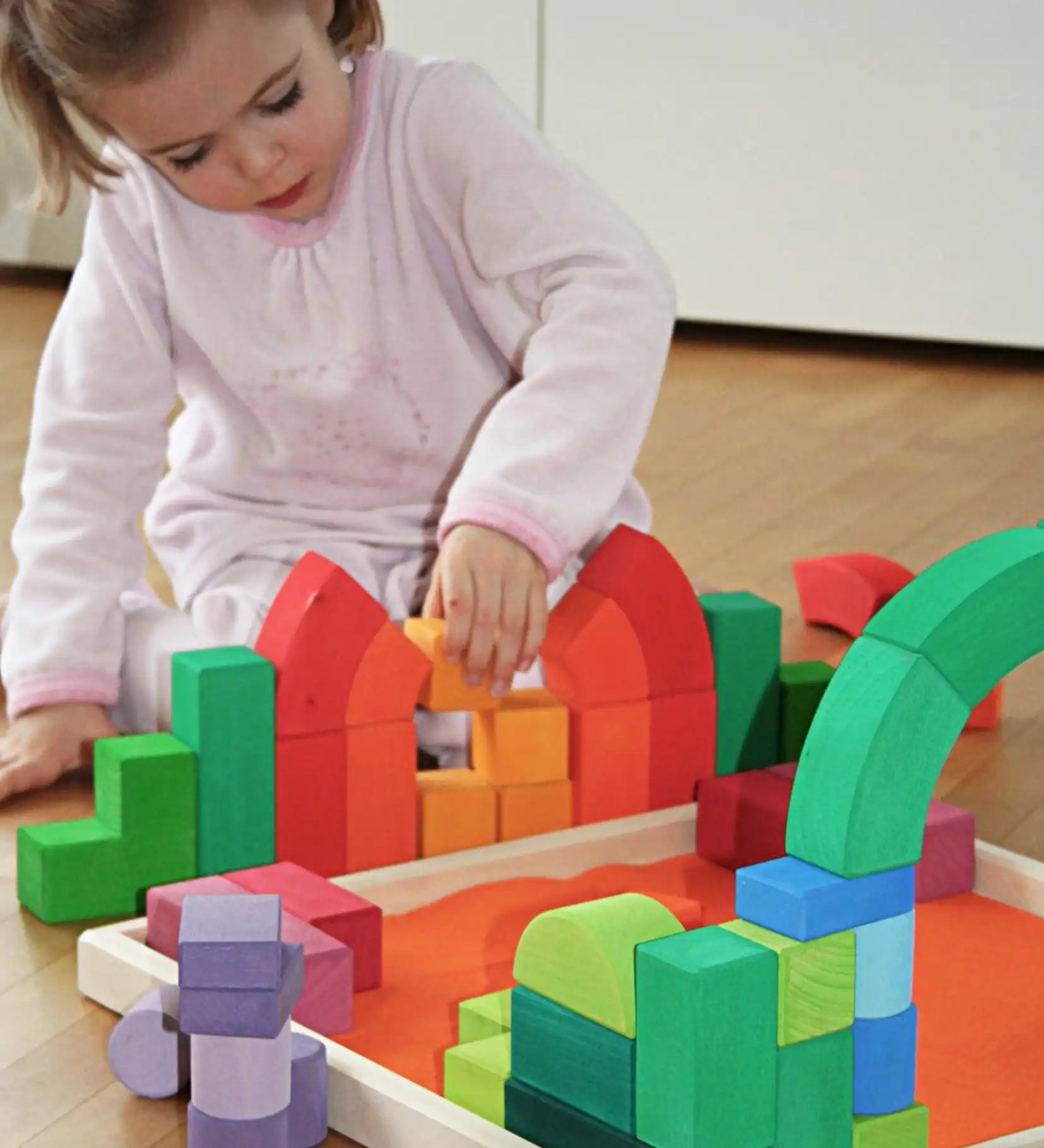 Child playing with the Grimm's large Romanesque building set.