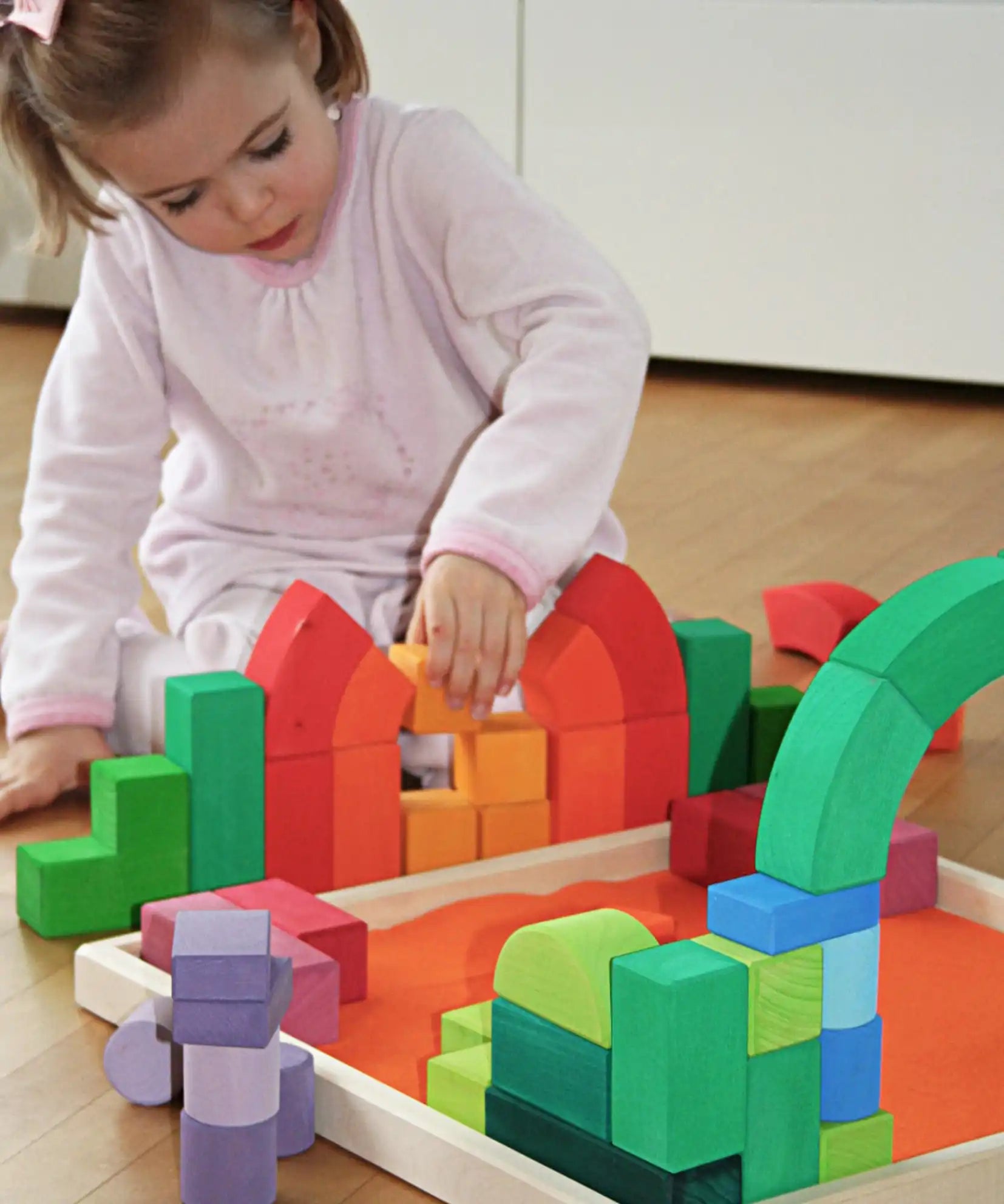 Child playing with the Grimm's large Romanesque building set.