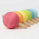 The Grimm's pastel spinning tops, arranged in a straight line in rainbow order. 