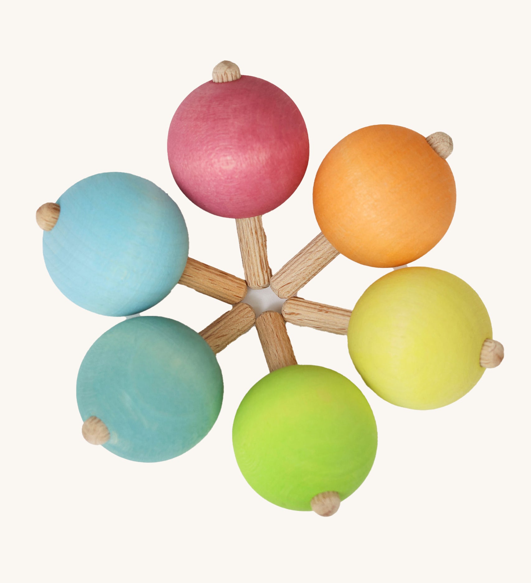 A set of six traditional wooden spinning tops from Grimm's, in pastel rainbow colours and arranged in a circle.