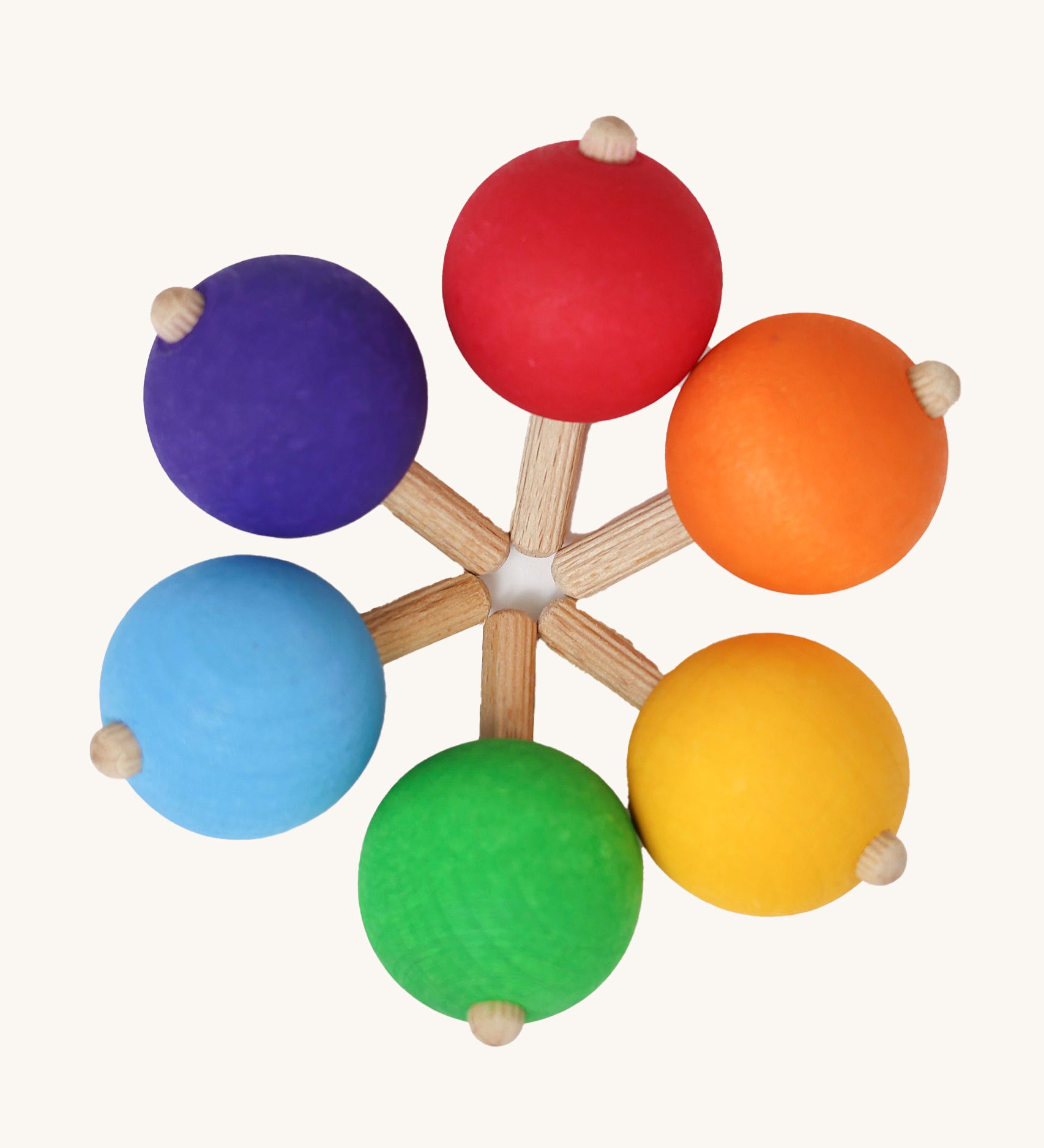 A set of six traditional wooden spinning tops from Grimm's, in rainbow colours and arranged in a circle.