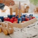 Adult stacking different building blocks on a Grimms small counting block in Grimm’s World of Numbers palette 