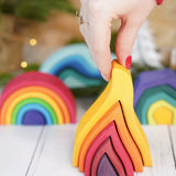 Adult hand holding the Grimms small wooden fire set showing scale 