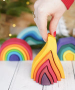 Adult hand holding the Grimms small wooden fire set showing scale 