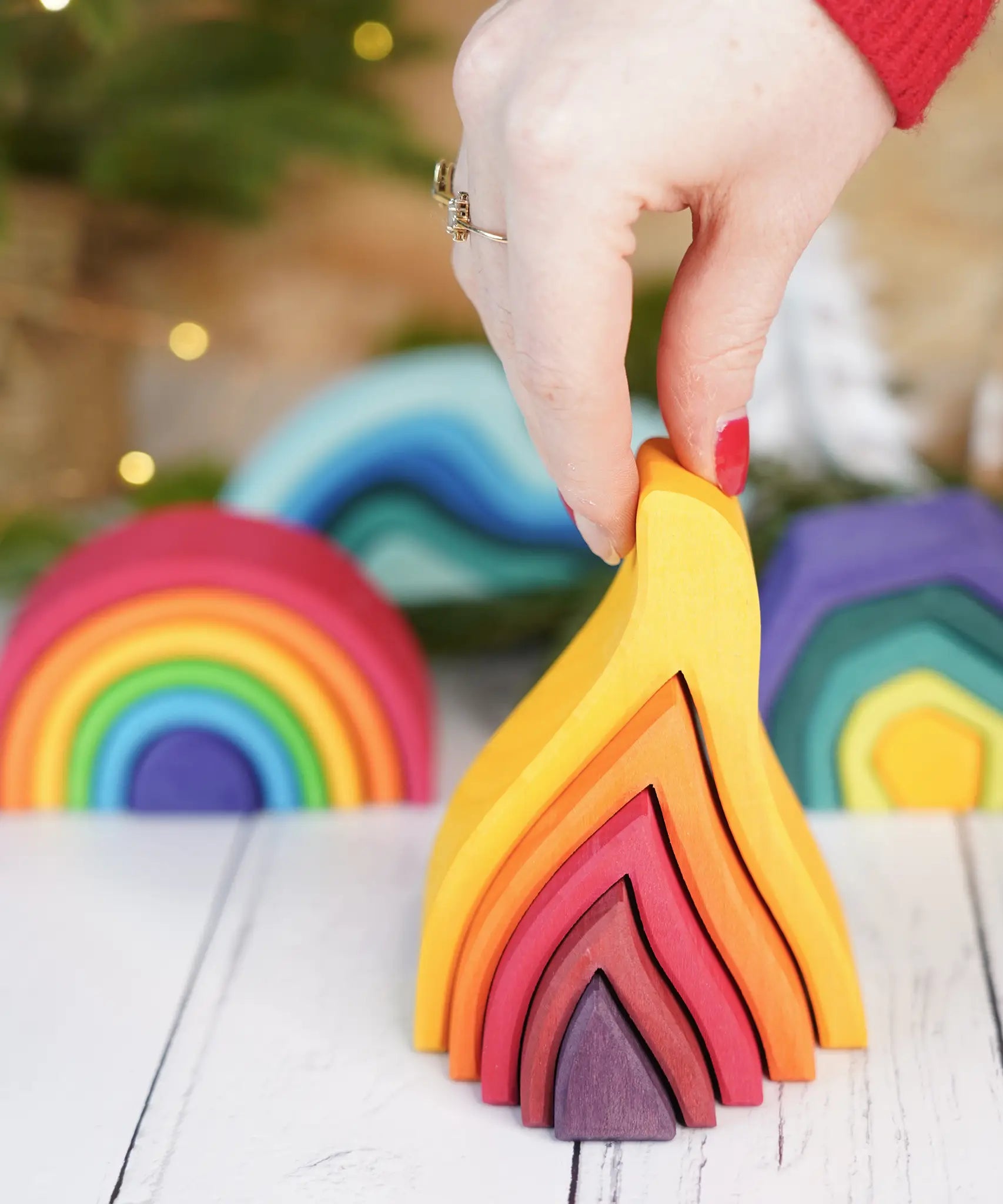 Adult hand holding the Grimms small wooden fire set showing scale 
