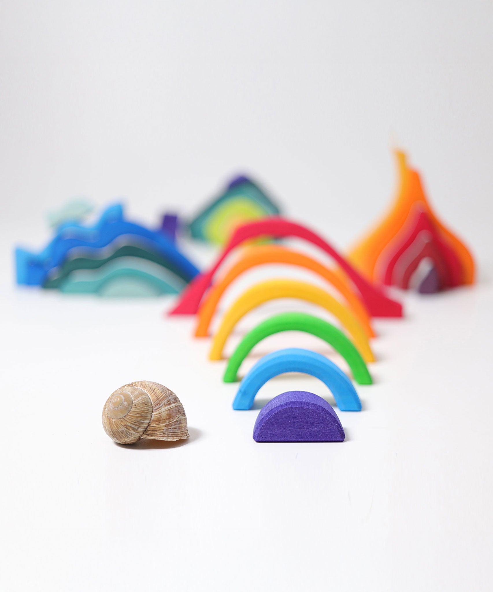 Pieces from the Grimm's Small 4 Elements Building Set taken out of the wooden storage and display case. The pieces of the rainbow element can be seen in the front.
