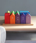 Grimm's small rainbow wooden houses set. 15 different colour houses in various sizes on a wooden plinth tray.