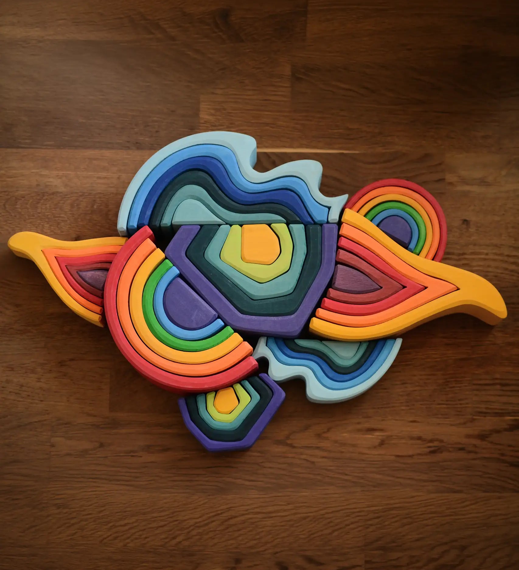 Grimms wooden mini and large elements set including water, earth, fire an a rainbow laid flat on a table