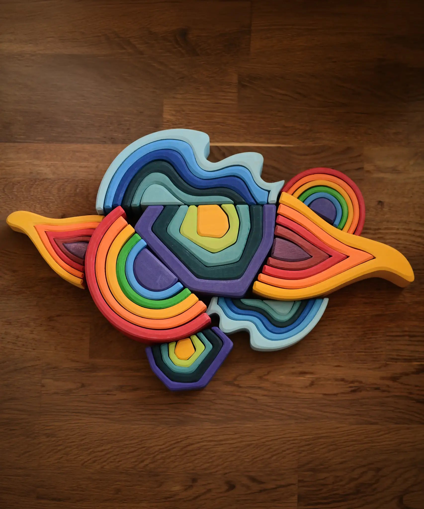 Grimms wooden mini and large elements set including water, earth, fire an a rainbow laid flat on a table