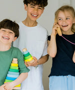 Children holding a small and large Grimms neon green conical stacking towers