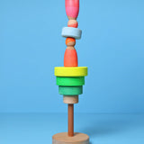 Loose small Grimms neon green conical pieces stacked with neon peg dolls balancing on top