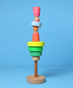 Loose small Grimms neon green conical pieces stacked with neon peg dolls balancing on top