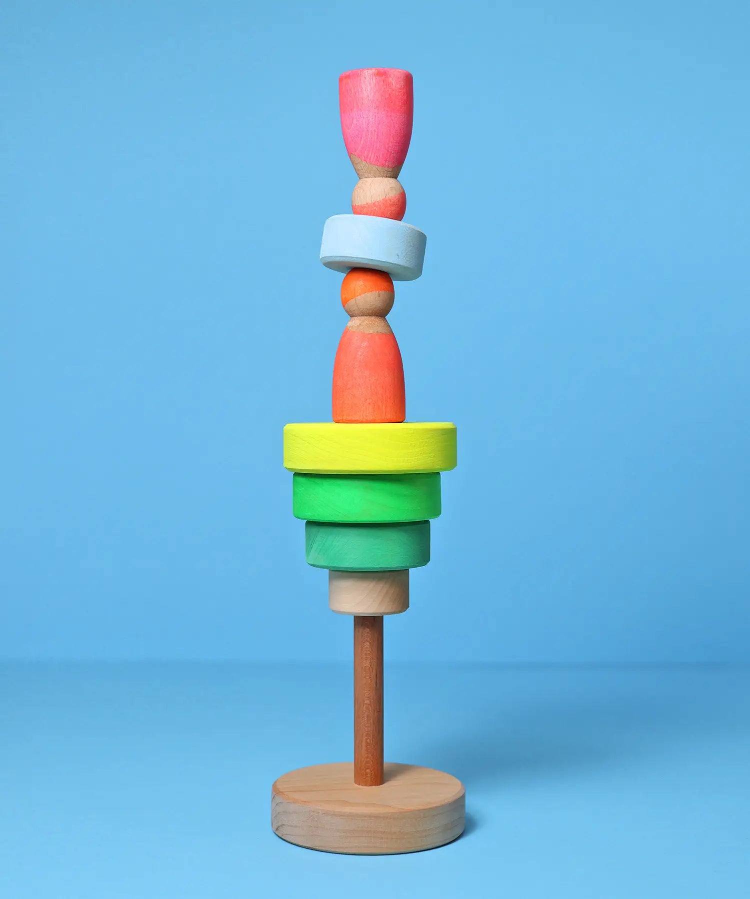 Loose small Grimms neon green conical pieces stacked with neon peg dolls balancing on top