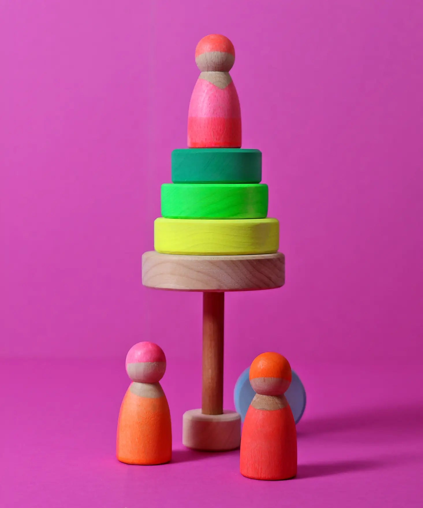 A tree made from loose wooden neon green Grimms conical tower pieces with a peg doll on top