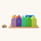 Grimm's small rainbow wooden houses set placed next to a snail's shell. 15 different colour houses in various sizes.