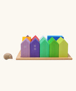 Grimm's small rainbow wooden houses set placed next to a snail's shell. 15 different colour houses in various sizes.
