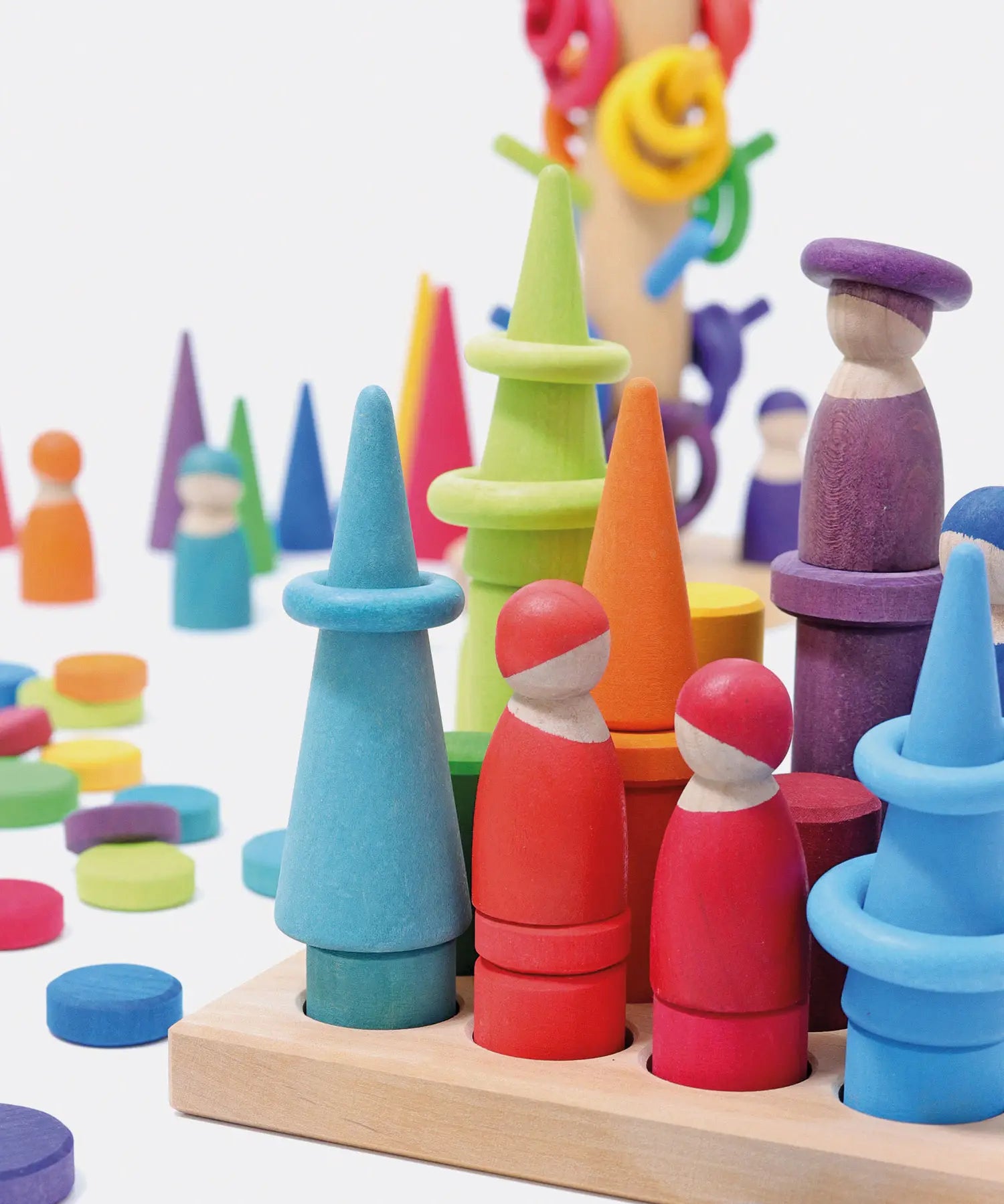 Open ended play set up using Grimms small stacking rollers, rings, coins and other loose blocks in a rainbow palette
