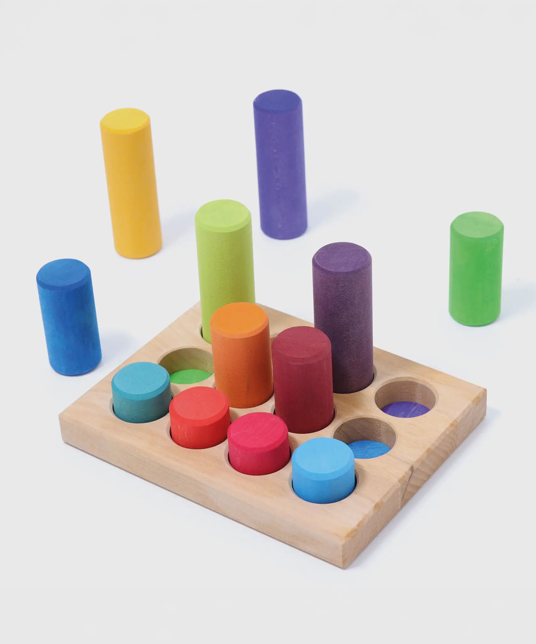 Loose Grimm's small building rollers in a rainbow palette next to a wooden sorting tray.
