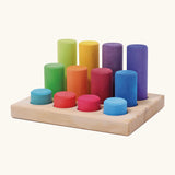 Grimm's small building rollers in bright rainbow colours in a wooden storage tray.