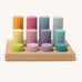 Different sized wooden Grimms pastel rollers in a wooden frame on a cream background.
