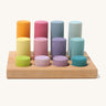 Different sized wooden Grimms pastel rollers in a wooden frame on a cream background.