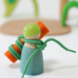A peg doll from the Grimms wooden small world play in the woods set with a piece of felt tied with a piece of string