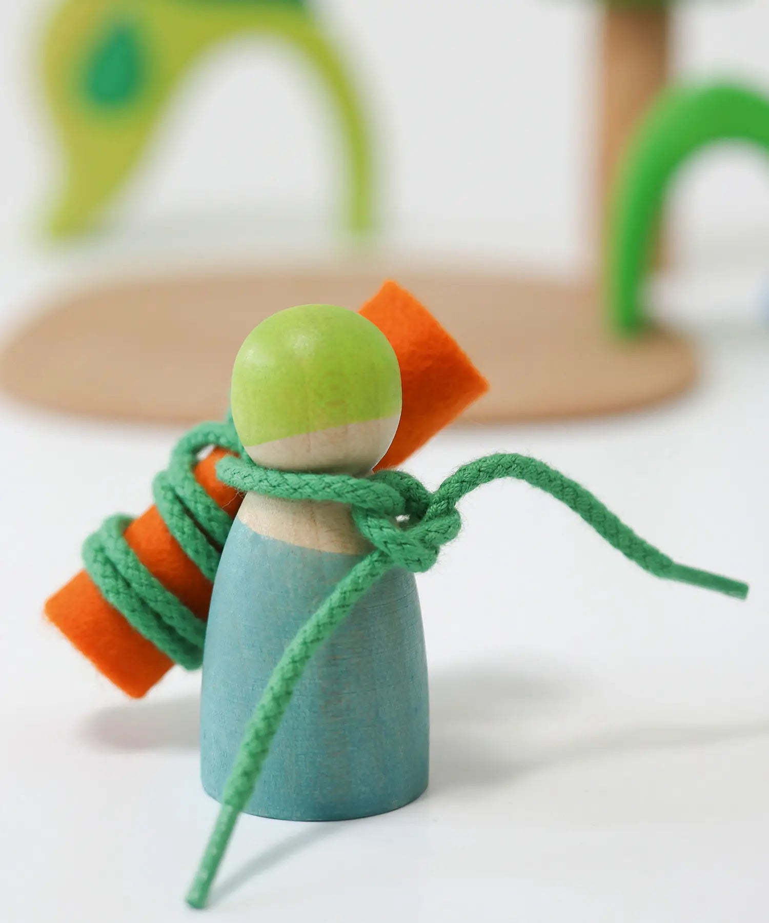 A peg doll from the Grimms wooden small world play in the woods set with a piece of felt tied with a piece of string