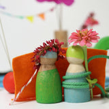 Wooden peg dolls from the Grimms small world play in the woods set with flowers on their heads