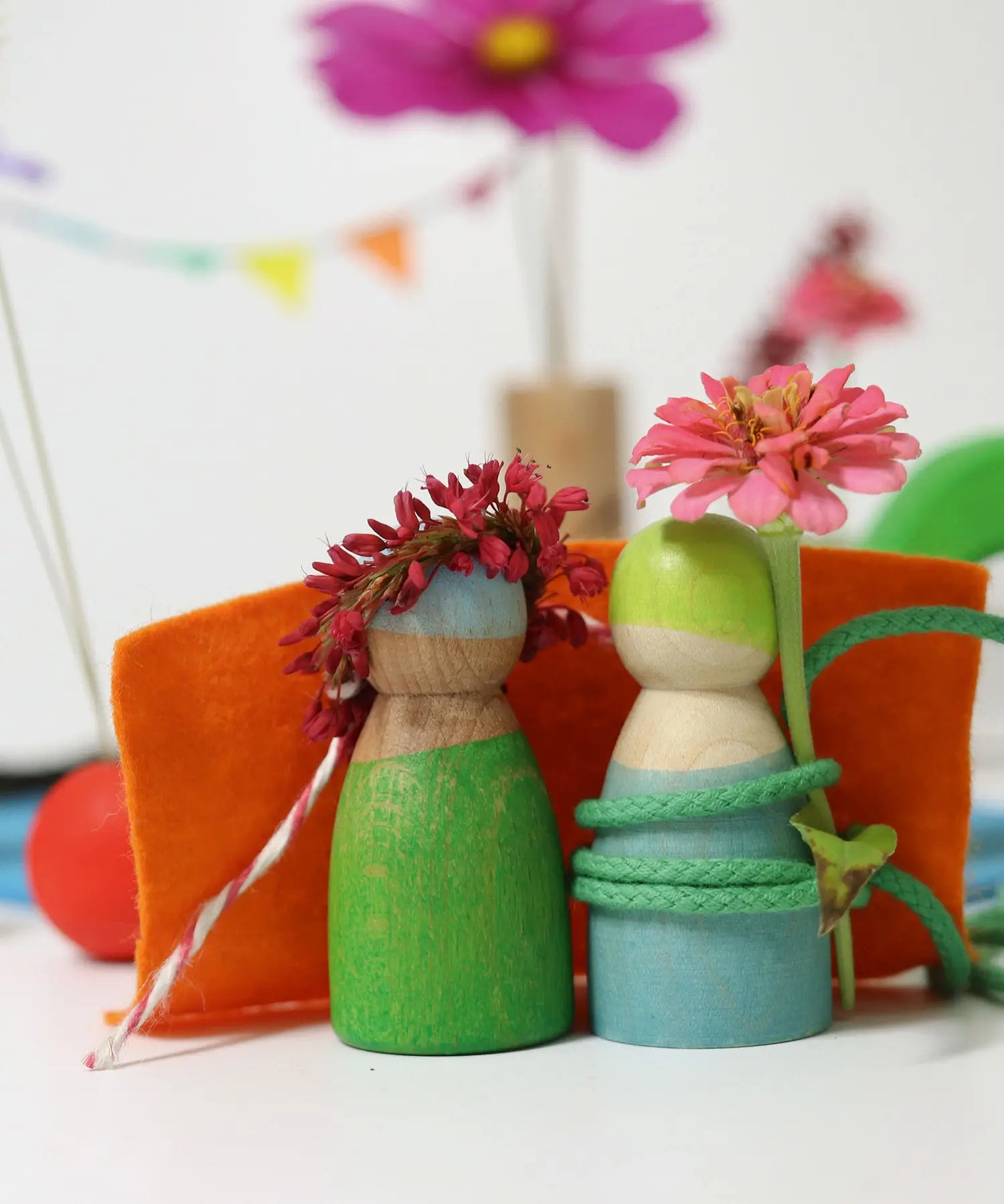 Wooden peg dolls from the Grimms small world play in the woods set with flowers on their heads