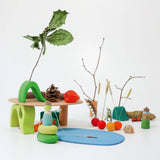 A display showing loose blocks from the Grimms small world play in the woods, peg dolls and woodland pieces