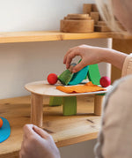 Child placing a wooden peg doll from the Grimms small world play in the woods set on the base 