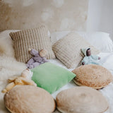 A violet, aqua and yellow Grimms soft Waldorf doll on a bed