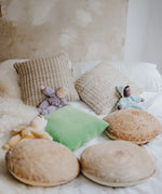 A violet, aqua and yellow Grimms soft Waldorf doll on a bed