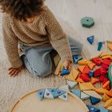 Child holding a blue Grimms sparkling mandala piece above its circular frame