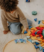 Child holding a blue Grimms sparkling mandala piece above its circular frame